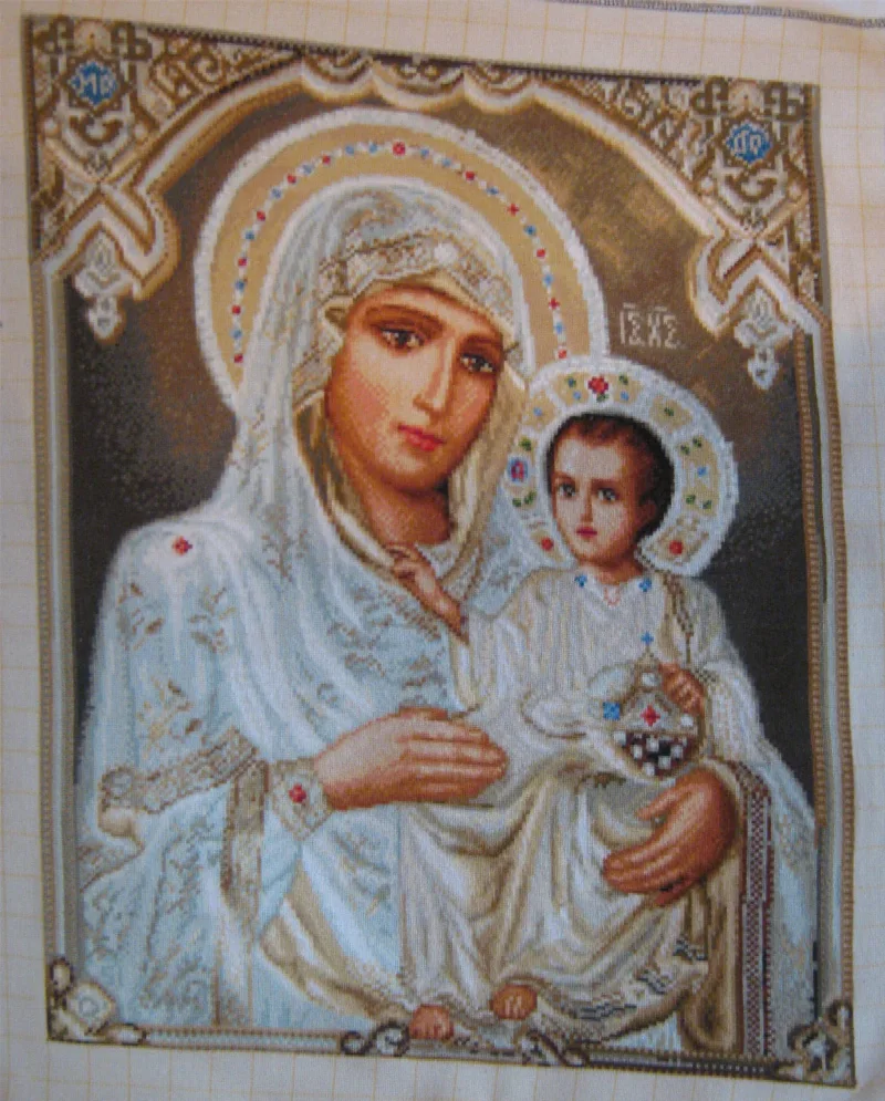 Maryja i Dzieciątko Jezus w jasnych wzorzystych szatach z dekorowanymi aureolami na tkaninie bez ramy