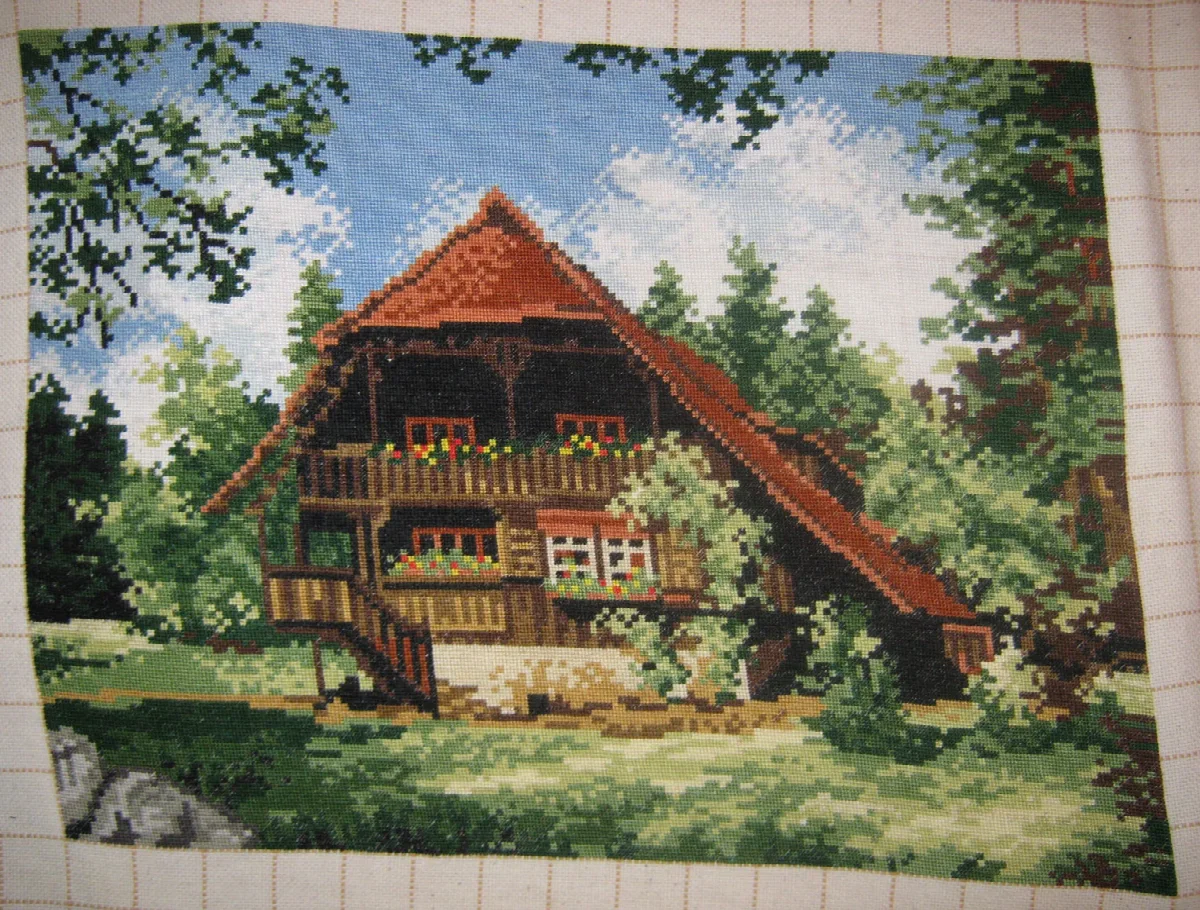Timber chalet with red roof and flowered balconies in a green woodland clearing